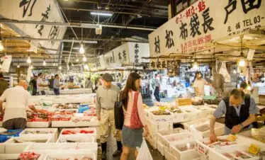 Tsukiji Outer Market in Tokyo with vendors selling fresh seafood and customers browsing